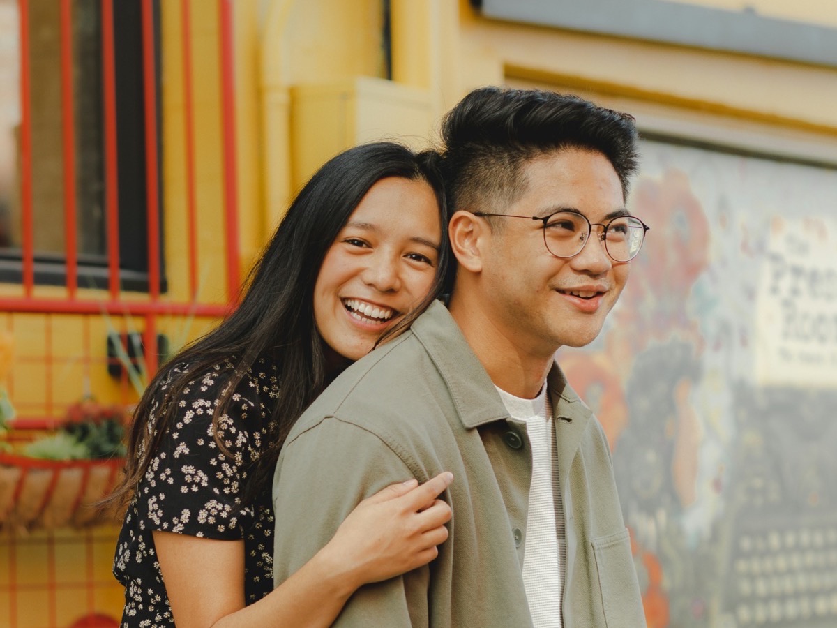 A young couple standing together in front of a painted wall